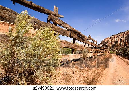 Stock Photography - View of traditional old wooden fence and red sandy road, sunny afternoon with blue sky, Pleasant Valley, Utah. Fotosearch