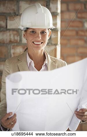 Architect holding plans at construction site View Large Photo Image Picture - Architect holding plans at construction site. Fotosearch