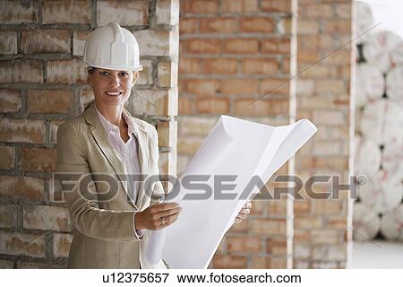 Stock Photo - Architect holding plans at construction site. Fotosearch