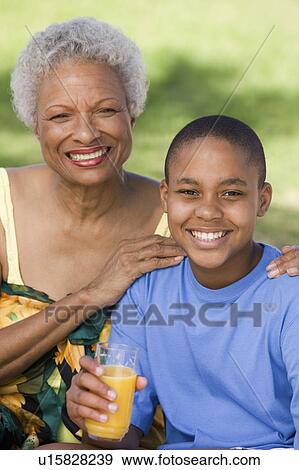 Boy (10-12) holding glass of juice, with grandmother, front view portrait. View Large Photo Image Stock Photo - Boy (10-12) holding glass of juice, with grandmother, front view portrait.. Fotosearch