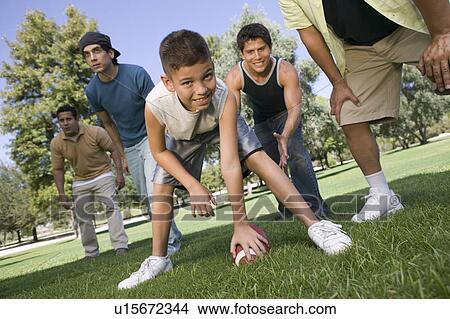 Boy (13-15) playing football with group of men. View Large Photo Image Picture - Boy (13-15) playing football with group of men.. Fotosearch