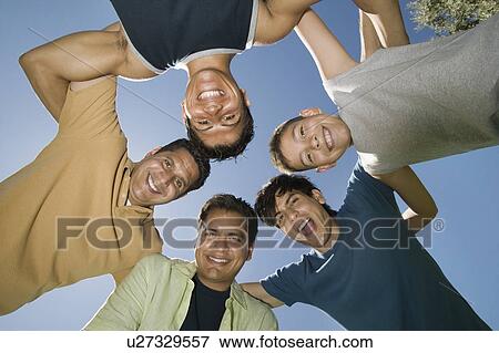 Stock Photo - Boy (13-15) with brothers and father in a huddle, view from below.. Fotosearch