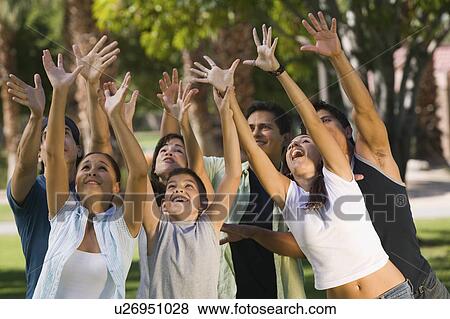 Stock Photo - Boy (13-15) with group of young adults, reaching upwards.. Fotosearch