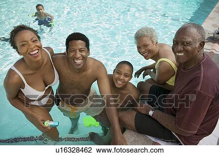 Stock Image - Boy (7-9) at swimming pool with parents and grandparents, elevated view portrait.. Fotosearch