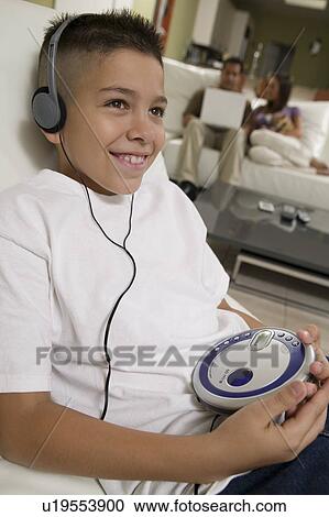Stock Image - Boy Listening to Music on Portable CD Player in living room. Fotosearch