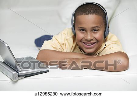 Boy on sofa Watching movie on Portable DVD Player, portrait View Large Photo Image Stock Image - Boy on sofa Watching movie on Portable DVD Player, portrait. Fotosearch