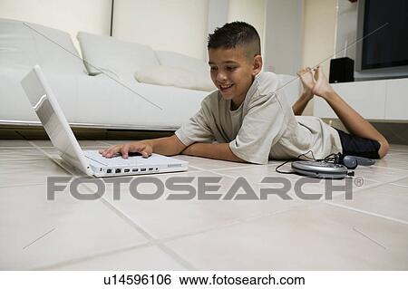 Boy Using Laptop on Floor in living room, ground view View Large Photo Image Stock Photograph - Boy Using Laptop on Floor in living room, ground view. Fotosearch