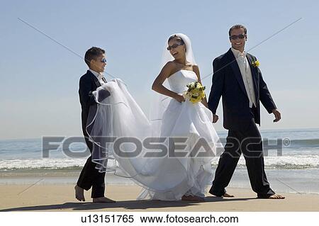 Stock Photography - Bride and Groom with brother walking on beach. Fotosearch