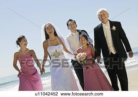 Stock Image - Bride and Groom with family on beach, (portrait). Fotosearch