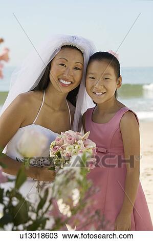 Stock Image - Bride and sister on beach, (portrait). Fotosearch