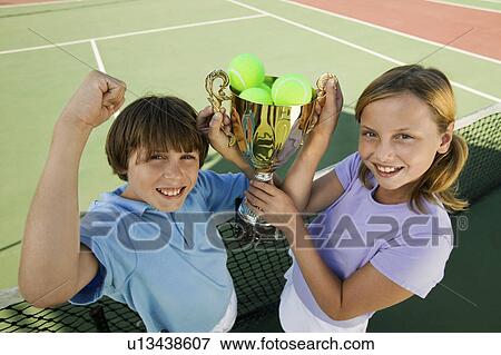 Stock Photo - Brother and Sister on tennis court holding up Trophy, portrait, high angle view. Fotosearch