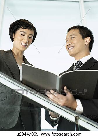 Stock Photography - Business colleagues reviewing documents while standing on stairs. Fotosearch
