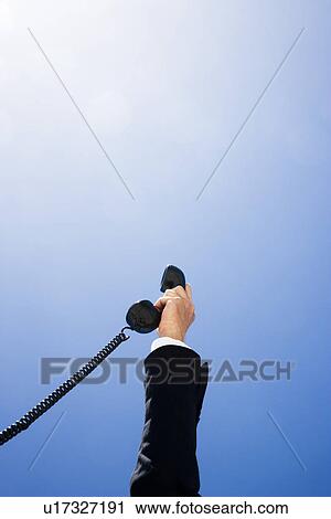 Business man holding telephone receiver against sky, close up of hand View Large Photo Image Stock Image - Business man holding telephone receiver against sky, close up of hand. Fotosearch