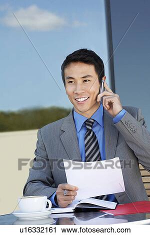 Businessman at outdoor Cafe, talking on phone, reviewing documents View Large Photo Image Stock Image - Businessman at outdoor Cafe, talking on phone, reviewing documents. Fotosearch