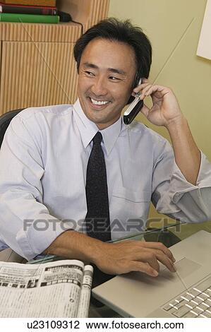 Stock Image - Businessman Using Cell Phone and Laptop. Fotosearch