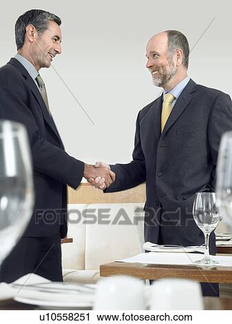 Businessmen shaking hands in restaurant View Large Photo Image Stock Image - Businessmen shaking hands in restaurant. Fotosearch