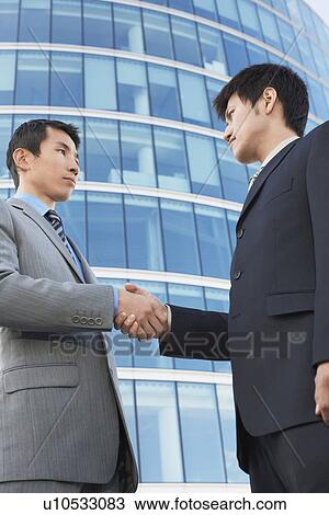 Businessmen Shaking Hands outside office building, low angle view View Large Photo Image Stock Image - Businessmen Shaking Hands outside office building, low angle view. Fotosearch