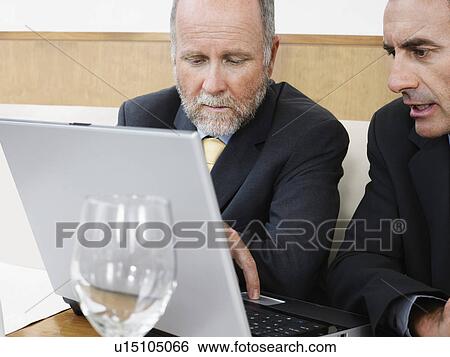 Stock Photograph - Businessmen using laptop in restaurant. Fotosearch