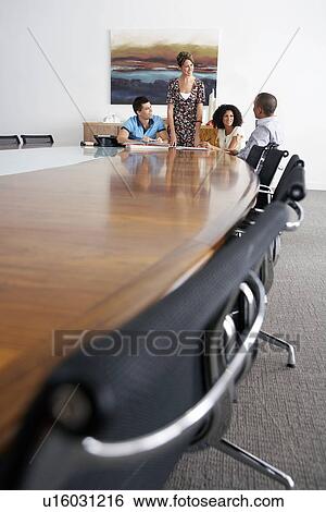 Stock Photograph - Businesspeople holding a meeting at the end of a conference table. Fotosearch