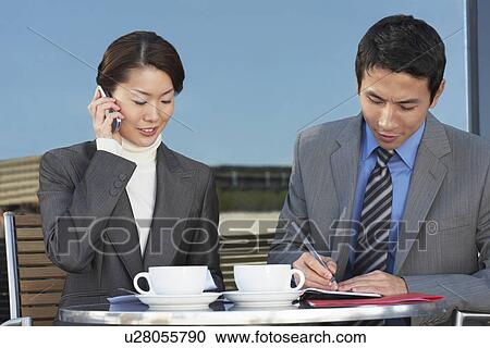 Businesspeople Meeting at outdoor Cafe, talking on phone, reviewing documents View Large Photo Image Stock Image - Businesspeople Meeting at outdoor Cafe, talking on phone, reviewing documents. Fotosearch