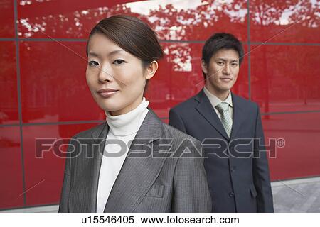 Stock Photography - Businesspeople Standing outside, beside red building. Fotosearch
