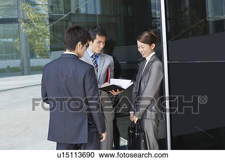 Businesspeople standing outside, looking over documents View Large Photo Image Stock Image - Businesspeople standing outside, looking over documents. Fotosearch