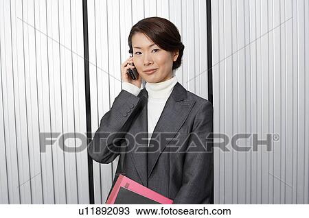Businesswoman holding paperwork, using Cell Phone View Large Photo Image Stock Image - Businesswoman holding paperwork, using Cell Phone. Fotosearch