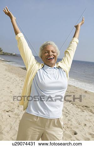 Stock Image - Cheerful middle-aged woman on beach. Fotosearch