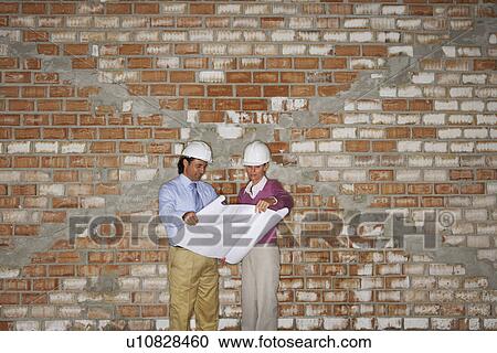 Stock Image - Construction manager and architect examining plans. Fotosearch