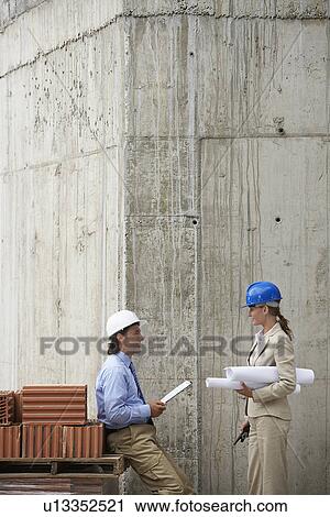 Stock Image - Construction manager and architect talking on site. Fotosearch