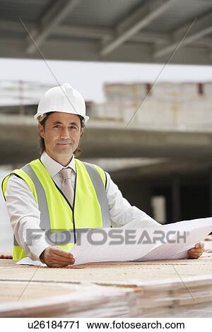 Stock Image - Construction worker holding building plans. Fotosearch
