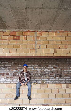 Picture - Construction worker sitting on brick wall. Fotosearch