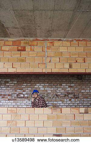 Stock Photo - Construction worker talking on cell phone on site. Fotosearch