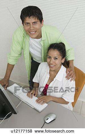 Couple at desk Using Computer, portrait, high angle view View Large Photo Image Stock Photo - Couple at desk Using Computer, portrait, high angle view. Fotosearch
