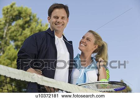 Stock Image - Couple at Tennis Net, portrait, low angle view. Fotosearch