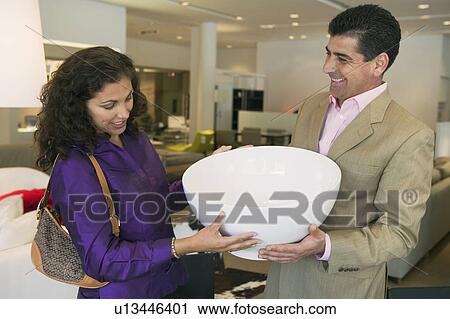 Stock Image - Couple Examining Large Bowl in furniture store. Fotosearch