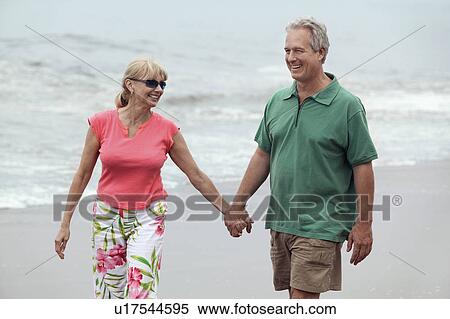 Stock Photography - Couple holding hands, walking on beach. Fotosearch