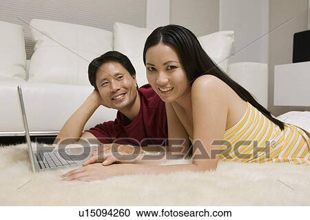 Couple lying on Rug with Laptop, portrait, ground view View Large Photo Image Stock Image - Couple lying on Rug with Laptop, portrait, ground view. Fotosearch