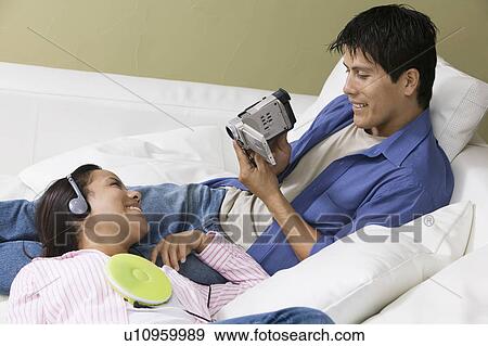 Couple on sofa, man filming partner View Large Photo Image Stock Photo - Couple on sofa, man filming partner. Fotosearch