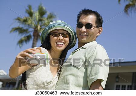 Stock Image - Couple photographing themselves, outdoors. Fotosearch