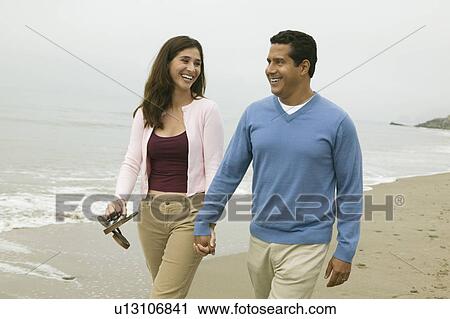 Stock Image - Couple Walking Together on Beach. Fotosearch