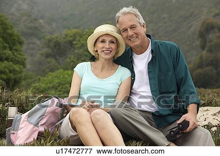 Stock Photo - Couple with binoculars in countryside, (portrait). Fotosearch