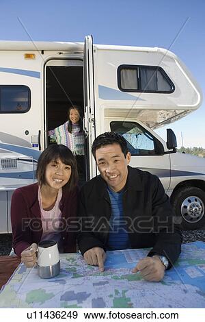 Stock Photo - Couple with daughter looking at map on picnic table outside RV. Fotosearch