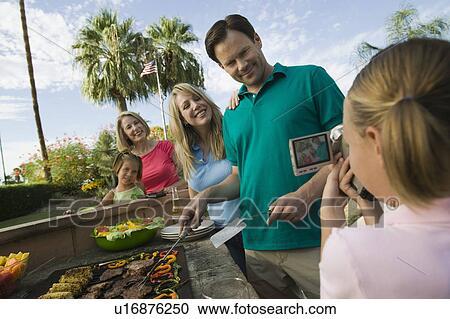 Daughter (7-9) video taping parents, grandmother, sister (7-9) at outdoor barbecue. View Large Photo Image Stock Image - Daughter (7-9) video taping parents, grandmother, sister (7-9) at outdoor barbecue.. Fotosearch