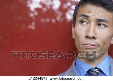 Doubtful Young Businessman against red, close-up View Large Photo Image Stock Photography - Doubtful Young Businessman against red, close-up. Fotosearch