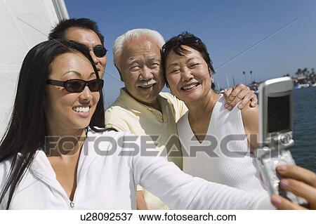 Family photographing themselves on sailboat View Large Photo Image Stock Photo - Family photographing themselves on sailboat. Fotosearch