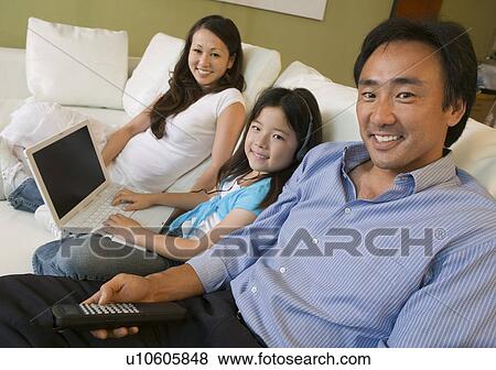 Stock Photo - Family Relaxing on sofa in Living Room, daughter with Laptop, portrait. Fotosearch