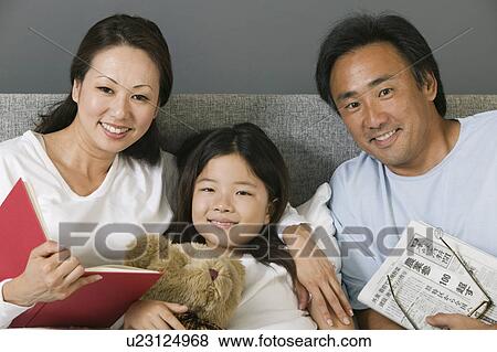 Stock Photo - Family Relaxing Together in Bed reading, portrait. Fotosearch
