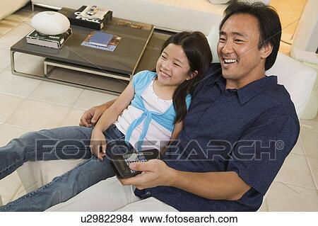 Picture - Father and Daughter Watching TV Together in living room, high angle view. Fotosearch