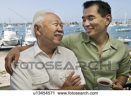 Stock Image - Father and son embracing at port. Fotosearch